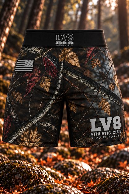 Front view of women's LV8 Woods shorts showing woodland camouflage, centered LV8 waistband branding, a monochrome American flag, and gray LV8 Athletic Club leg lettering.